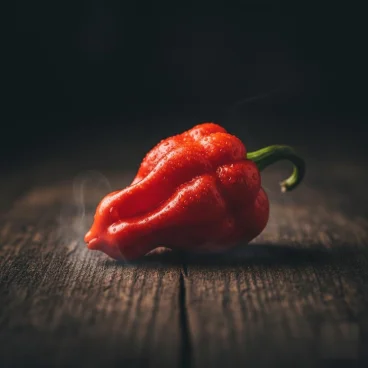 Piment rouge frais avec de la vapeur sur une surface en bois sombre