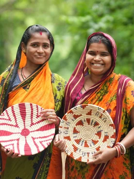 Deux artisanes indiennes souriantes présentant des vanneries colorées en fibres sauvages